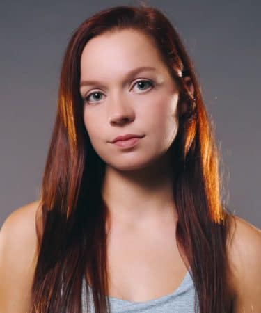 A woman with long red hair and brown eyes.
